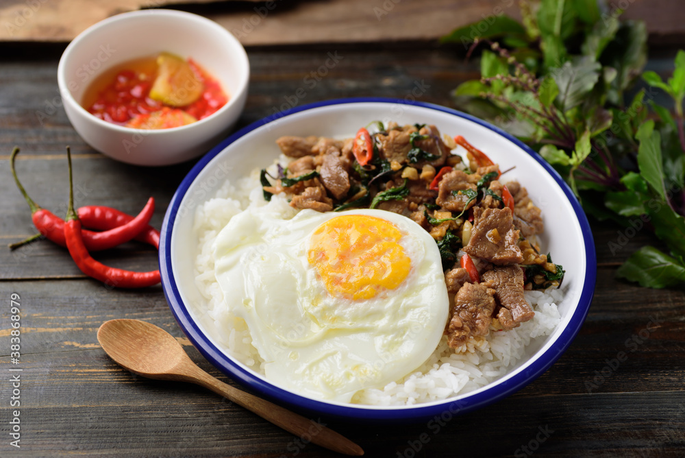 Thai food (Pad Kaprao Moo Kai Dao), Stir fried pork with basil and fried egg on cooked rice eating with chili in fish sauce Thai food (Pad Kaprao Moo Kai Dao), Stir fried pork with basil and fried egg on cooked rice eating with chili in fish sauce
