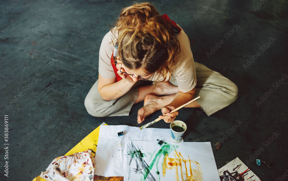 Top view of a female artist sitting on the floor in the studio and ...
