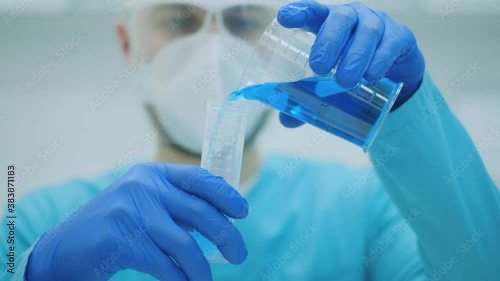 Flask in scientist hand with dropping liquid to test tube. Laboratory technician at the work Flask in scientist hand with dropping liquid to test tube. Laboratory technician at the work