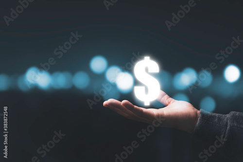 Businessman holding virtual US dollar sign with beautiful bokeh background. USD is main exchange currency in the world.