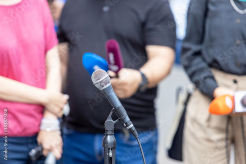 Microphone in the focus, journalists at news conference or media event in the background