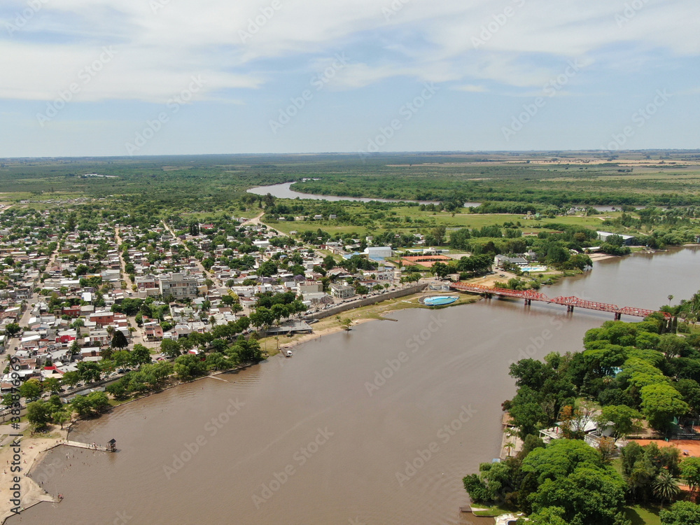 Vista aérea de un pequeño pueblo de casas bajas, con un río que lo atraviesa.