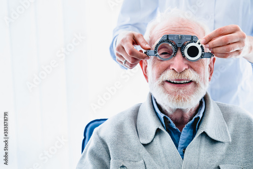 Portrait of a happy mature male patient undergoing vision check with special ophthalmic glasses photo