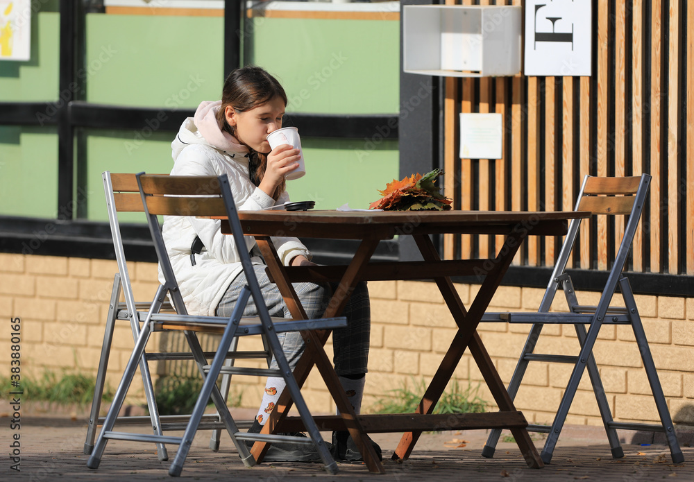 young girl drinking tea in autumn outdoors
