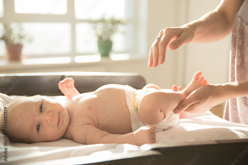 Mother massaging legs of her little baby lying on a bed Mother massaging legs of her little baby lying on a bed