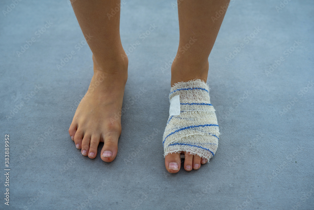 The eight-year-old boy stay with the bandaged heel. Grey background