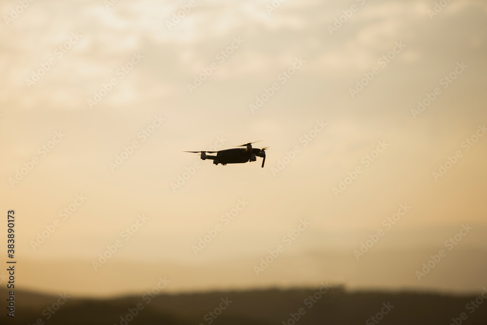 Silhouette of a drone flying during Sunset