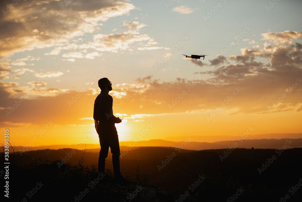Silhouette of a man piloting a drone on A Rural Setting during sunset