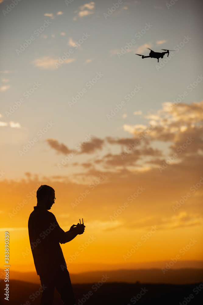 Ταπετσαρία Silhouette of a man piloting a drone on A Rural Setting during sunset