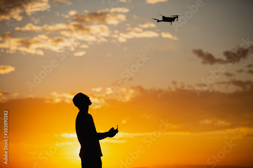 Silhouette of a man piloting a drone on A Rural Setting during sunset