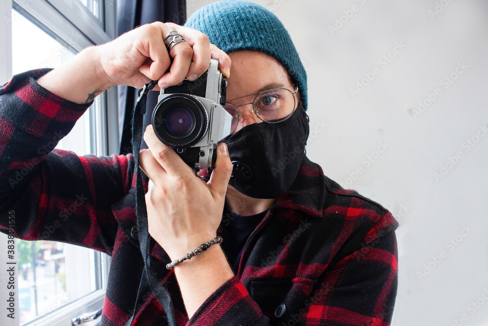 Guy in a fashionable outfit using his analog camera while he is wearing a face mask. Guy in a fashionable outfit using his analog camera while he is wearing a face mask.