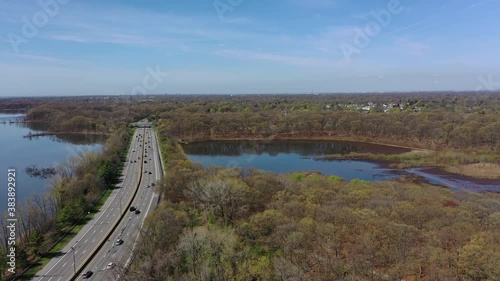Wallpaper Mural An aerial view over reflective lakes during a clear day. The drone camera dolly out over one of the lake, along a parkway. The parkway below to the left of the shot has car traffic that is moderate. Torontodigital.ca