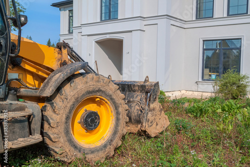 bulldozer is being prepared to demolish an illegally built private house in natural area. Close - up photo of tractor bucket in front of cottage entrance photo