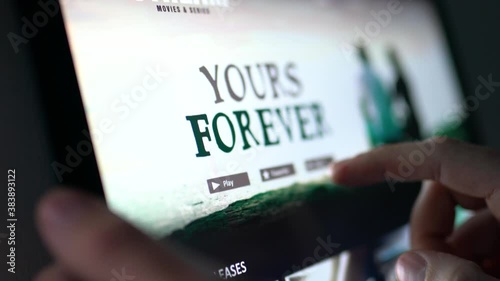 Movie stream service online. Man choosing series or film with tablet and touch screen. Streaming on demand video or watching an episode of a tv show with mobile device. All content is made up.