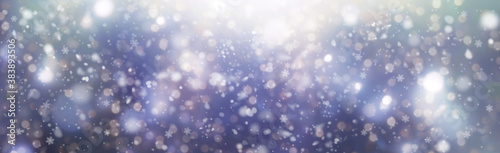 White snowflakes on a blue bokeh background fall from the sky - Christmas and winter background panorama 