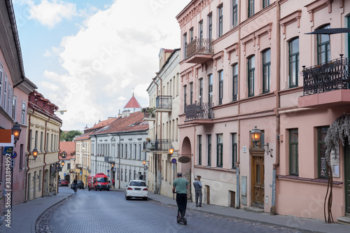A view of Uzupio street in Uzupis, Vilnius, Lithuania. People are using green transportation: a bicycle and an electric scooter.
