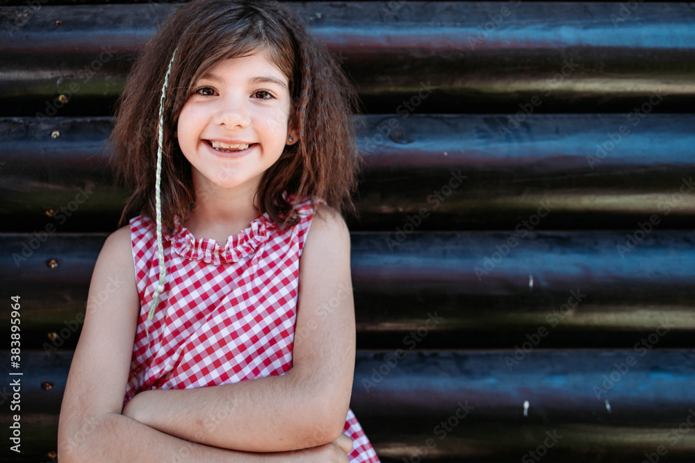 Portrait of a little brunette girl in checkered red dress smiling. Copy space