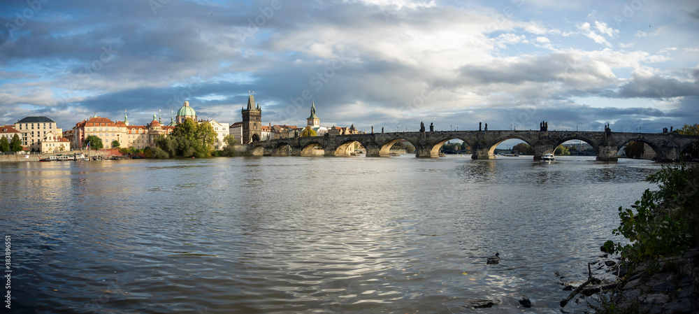 moving  cinematic shot of Charles Bridge and flowing Vltava river at sunset in the center of Prague in the Czech Republic