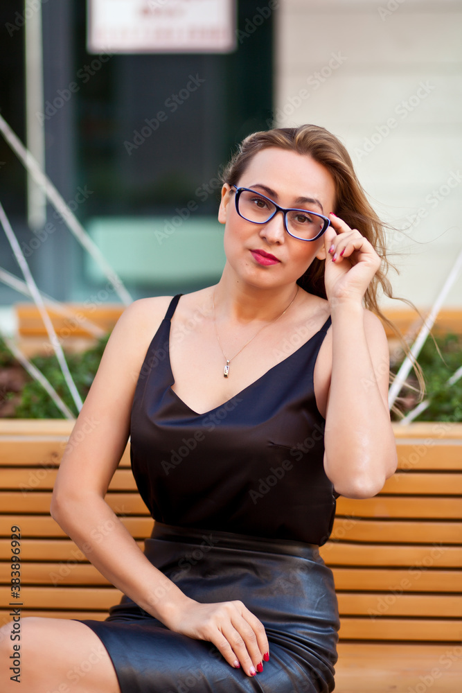 Pretty woman in a glasses sitting on the bench.