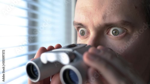 Surprised man with binoculars. Curious guy with big eyes. Nosy neighbour stalking or snooping secrets, gossip and rumour. Silly funny face. Shocked about unbelievable news. Stalker peeping people. photo