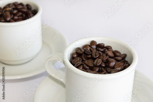Coffee beans in two coffee cups   on white isolated background.Closeup view.