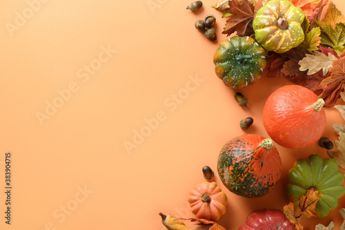 Festive composition of pumpkins, colorful leaves on orange background with space for text. Thanksgiving Day and Halloween template. View from above.