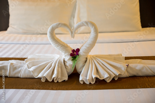 Fototapeta Naklejka Na Ścianę i Meble -  The white towel folded into swan shape and placed like heart shape on bed, luxury room hotel