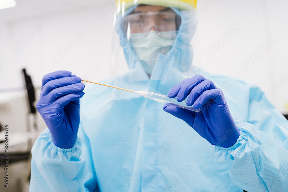 Medical scientist in PPE suit uniform holding swab coronavirus test in laboratory Medical scientist in PPE suit uniform holding swab coronavirus test in laboratory