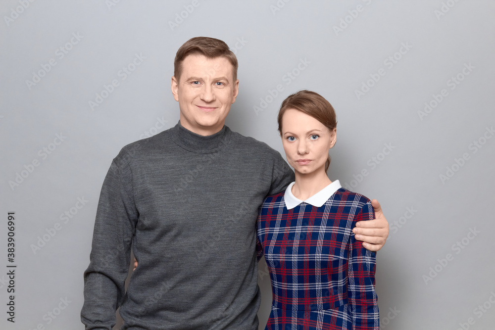Portrait of serious woman and joyful man hugging each other Portrait of serious woman and joyful man hugging each other