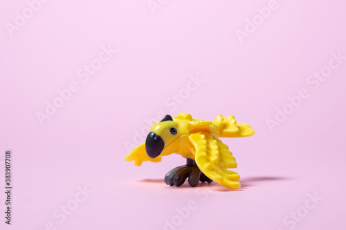 Toy parrot. Yellow toy parrot on a pink background. Plastic parrot