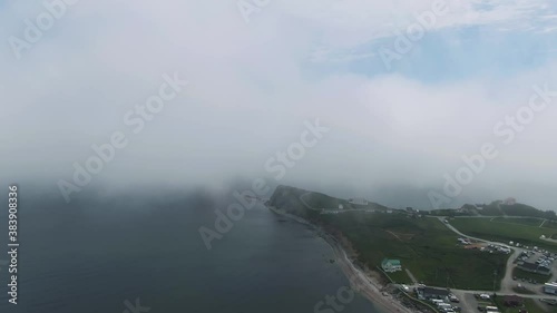 The City Of Perce By The Calm Water Of Saint Lawrence Gulf Covered With Clouds On A Foggy Morning In Quebec Canada. - Aerial Drone Shot photo