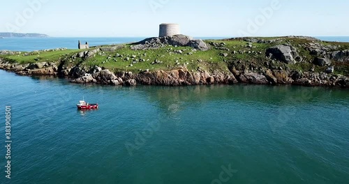Aerial footage of little red fishing boat catching fish near Dalkey Island and Coliemore harbour on sunny day. photo