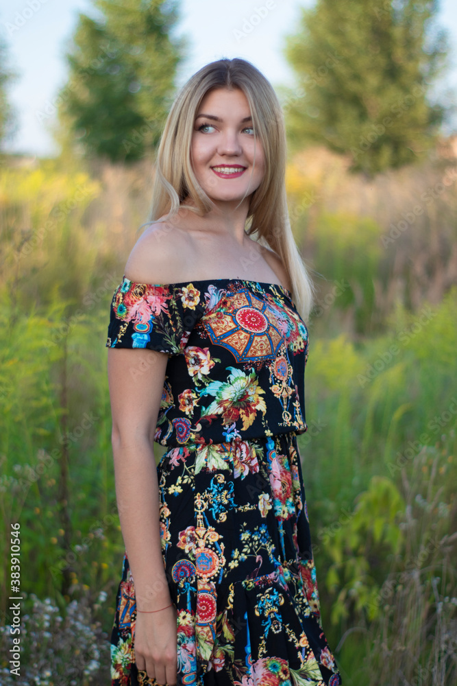 overlight bright portrait of a charming attractive blonde in flowery dress in the field. overlight bright portrait of a charming attractive blonde in flowery dress in the field.