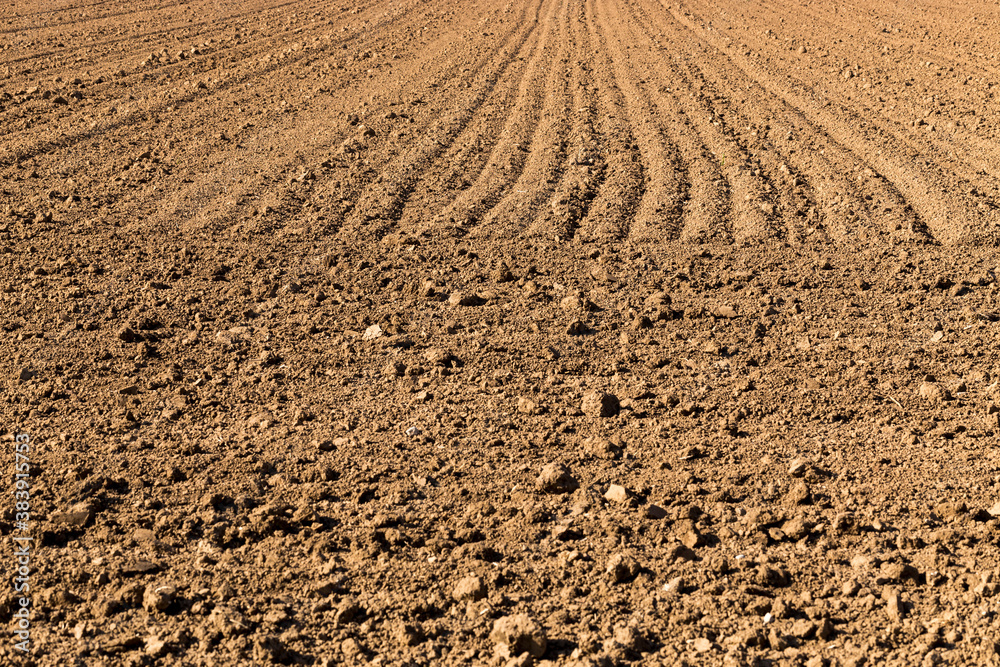 Full frame view of plowed agriculture field; naked light brown soil with rotary blade tracks, located in the German state of Baden-Württemberg Full frame view of plowed agriculture field; naked light brown soil with rotary blade tracks, located in the German state of Baden-Württemberg