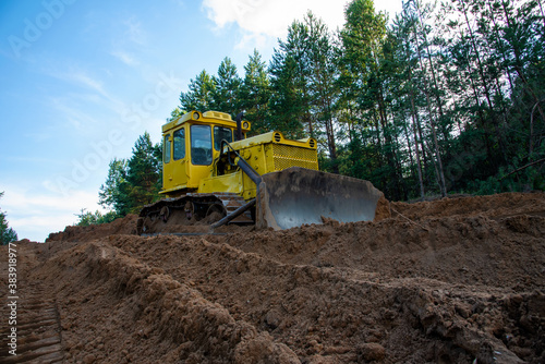 Dozer during clearing forest for construction new road . Yellow Bulldozer at forestry work Earth-moving equipment at road work, land clearing, grading, pool excavation, utility trenching © MaxSafaniuk