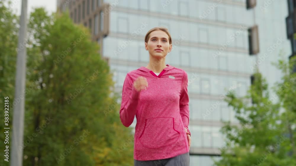 Medium shot of athletic young woman running down city street during daily jogging workout