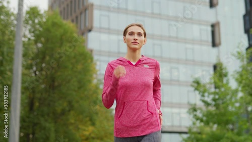 Medium shot of athletic young woman running down city street during daily jogging workout