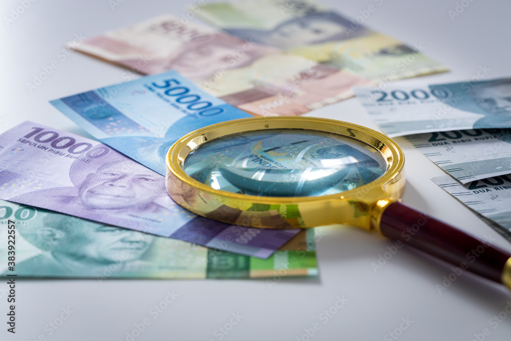 Indonesian money, Rupiah, Paper banknotes, Different values on which the magnifying glass lies Indonesian money, Rupiah, Paper banknotes, Different values on which the magnifying glass lies