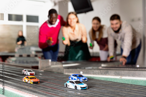 Slot car racing track. Emotional players drive toy cars in the background