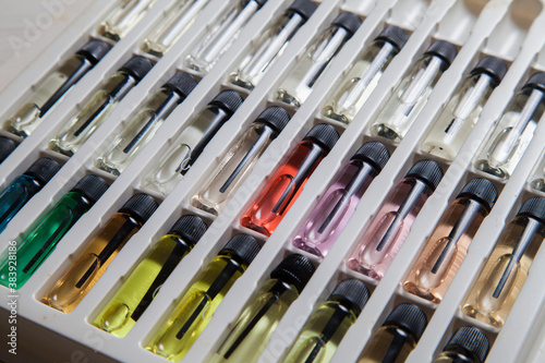 Sample of colored perfume bottles with different types of fragrances and aromas in a makeup case on the table. Beauty concept. Feminine concept. Colorful concept.