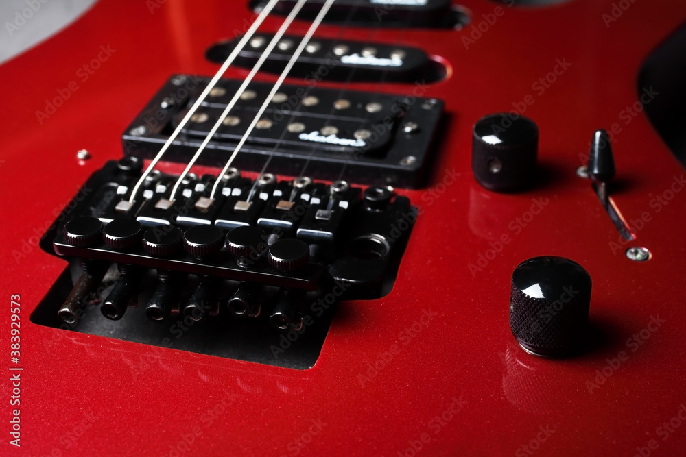Iron bridge for securing and tensioning the strings. Red electric guitar close up, selective focus. Iron bridge for securing and tensioning the strings. Red electric guitar close up, selective focus.
