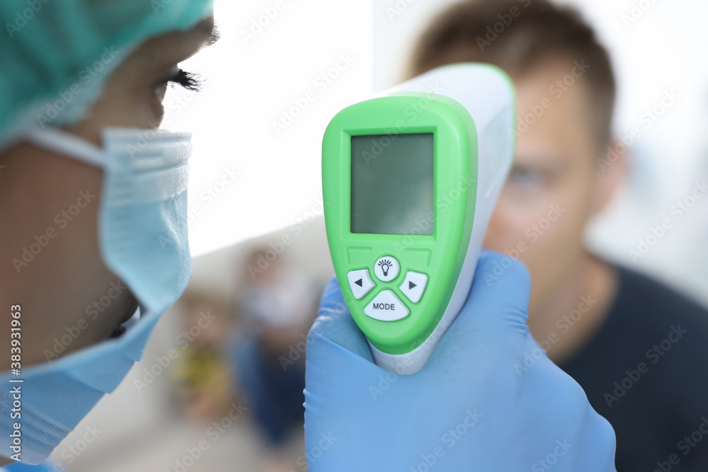 Doctor in a protective medical mask measures temperature of patient. First symptoms of disease concept Doctor in a protective medical mask measures temperature of patient. First symptoms of disease concept
