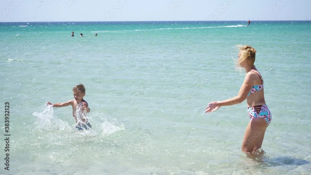 Happy family has fun playing in the sea creating splashes. A boy and his mother are having fun on their vacation at the sea. Happy family has fun playing in the sea creating splashes. A boy and his mother are having fun on their vacation at the sea.