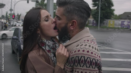 Middle-aged man and woman in love kissing on the street of a busy city in autumn in cloudy weather. A man in a sweater kissing a woman in a coat.