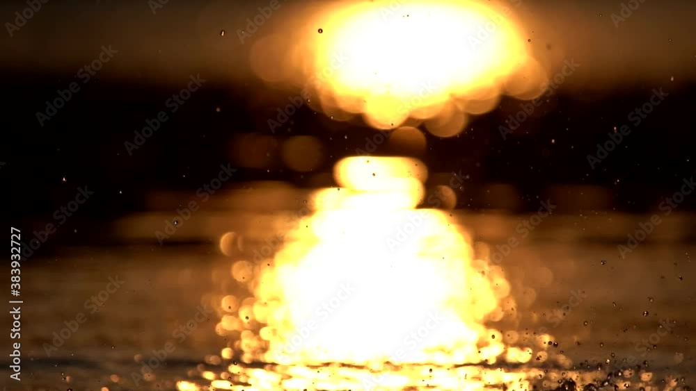 Slow motion of water splashing on lake surface against sunlight Slow motion of water splashing on lake surface against sunlight