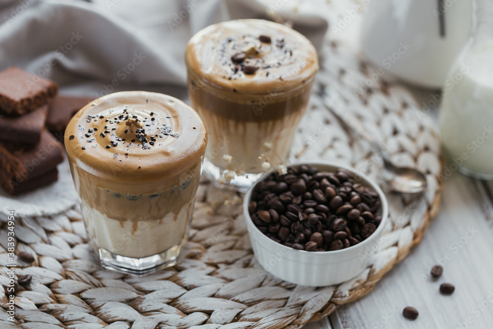 Glass of Iced Dalgona Coffee, trendy fluffy creamy whipped coffee and milk on white wooden background. Glass of Iced Dalgona Coffee, trendy fluffy creamy whipped coffee and milk on white wooden background.
