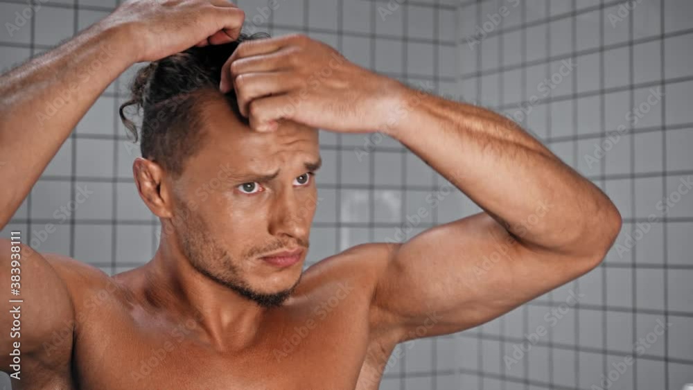 Man touching hair in bathroom at home Man touching hair in bathroom at home