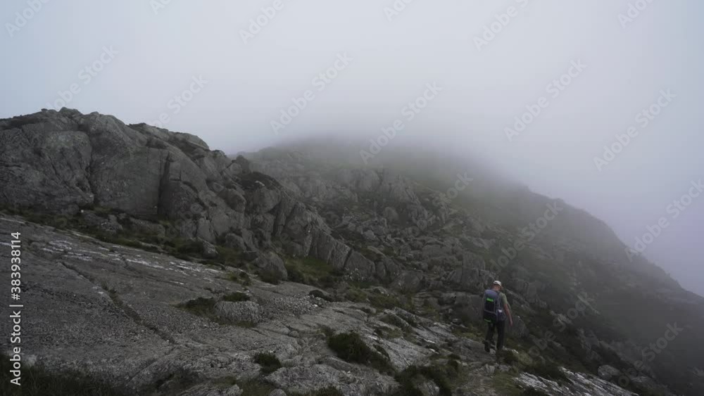 A man climbing a misty mountain in North Wales A man climbing a misty mountain in North Wales