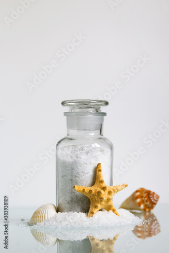 Bath sea salt in glass bottle on white background. SPA product. Home care. Vertical layout.