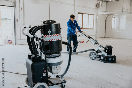 Construction worker using machine polishing surface floor smoothing and finishing hardener or epoxy concrete in the factory photo
